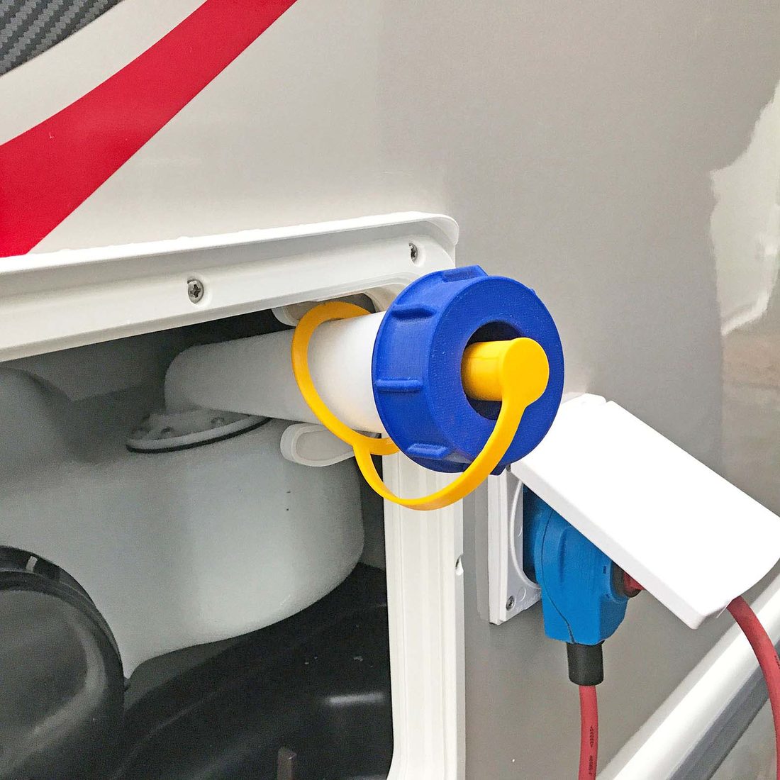 Blauer WAFA-Tankadapter am Einfüllstutzen eines Wohnmobils, daran eine gelbe Schlauchkupplung